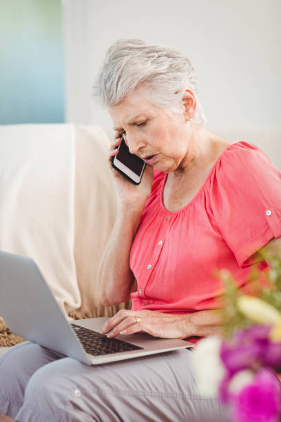 istock Senior woman talking on phone and using laptop 675176910