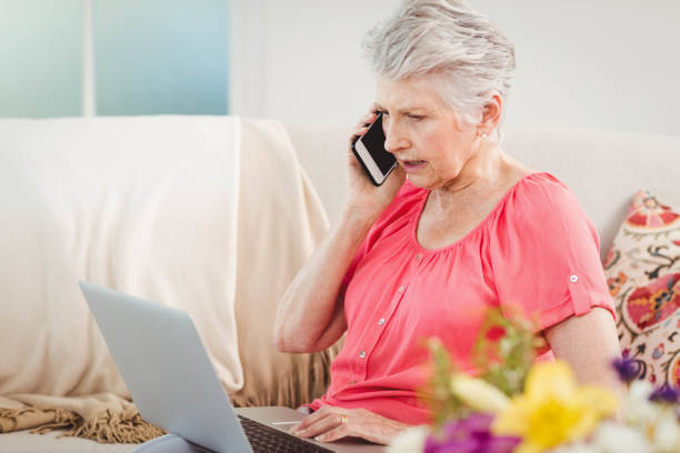 istock Senior woman talking on phone and using laptop 675176922