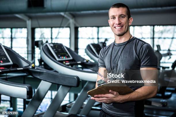 Muscular Trainer Writing On Clipboard Stock Photo - Download Image Now - Fitness Instructor, Gym, Health Club