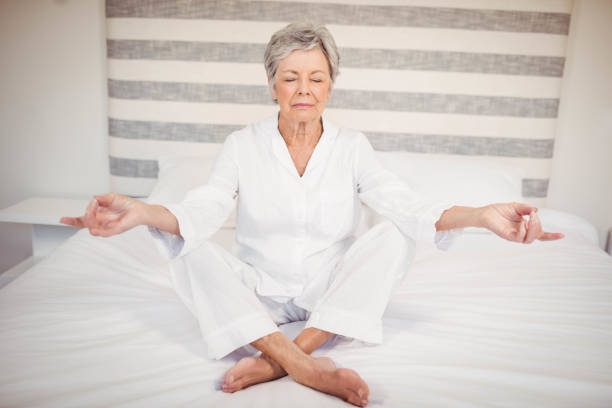 istock Senior woman meditating on bed 675179564
