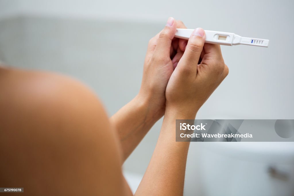 Woman holding a pregnancy test Close-up of Woman holding a pregnancy test in the bathroom Pregnancy Test Stock Photo