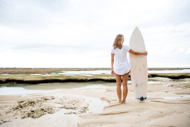 istock Woman Standing on Sand Beach With Surfboard 675199102