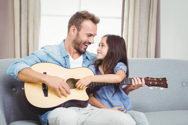 istock Man playing guitar with daughter at home 675200074