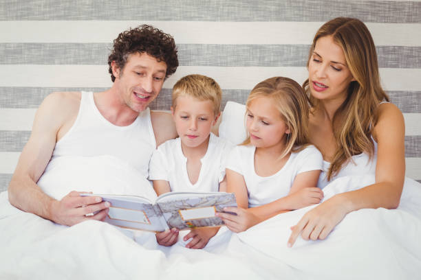 istock Family reading book on bed 675200664