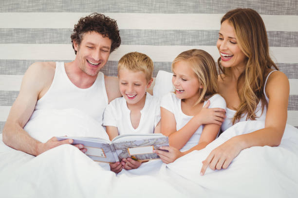 istock Happy family reading book on bed 675200672