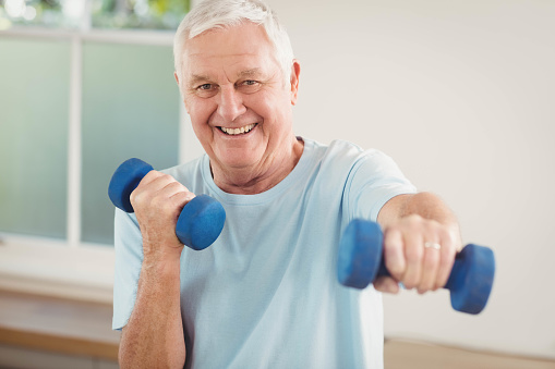 Portrait of senior man exercising with dumbbells at home