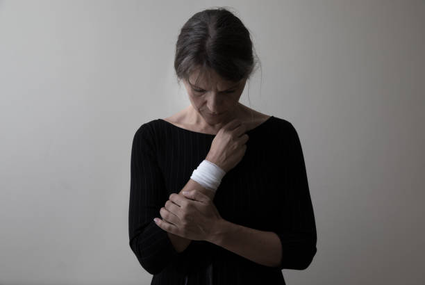 Middle age woman showing her bandaged wrist. Middle age woman showing the scars of self harm. self harm photos stock pictures, royalty-free photos & images