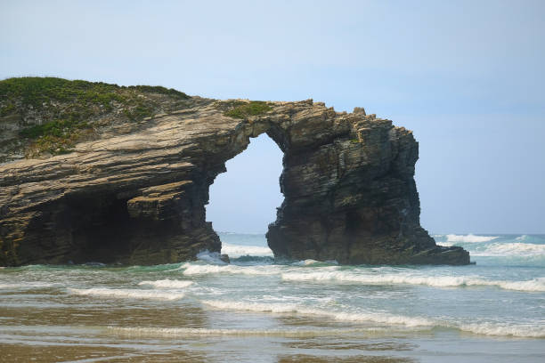 istock Cliffs and detached arch-shaped rock in the ocean 675226794