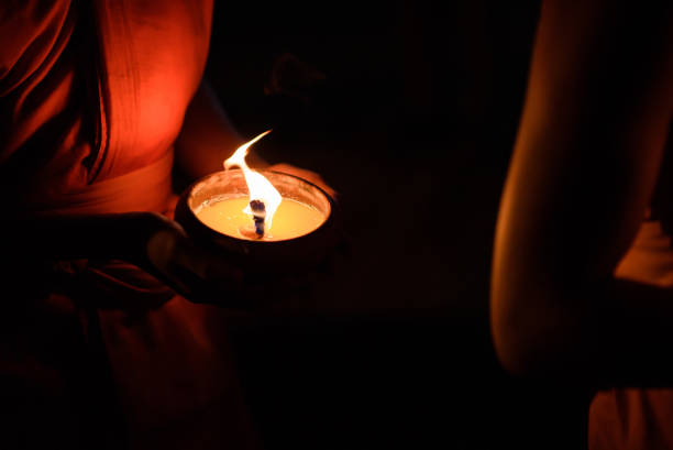 istock Buddhist monk hands holding candle cup in the dark 675233478