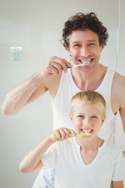 portrait of father and son brushing teeth - human teeth child smiling family imagens e fotografias de stock