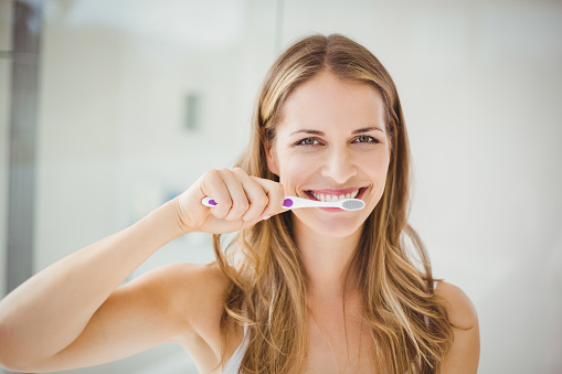 Portrait of beautiful young woman brushing teeth