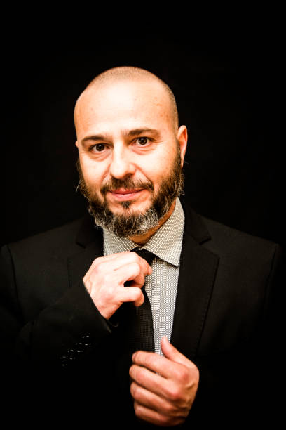 istock Handsome, bald man with beard,  in suit and tie, on black background 675239896