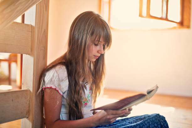 Cute little girl aged 10 reading a book.\n
