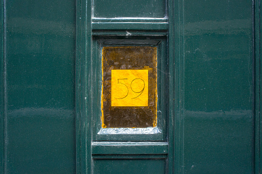 House number fifty nine, behind a decorative glass window in a door.