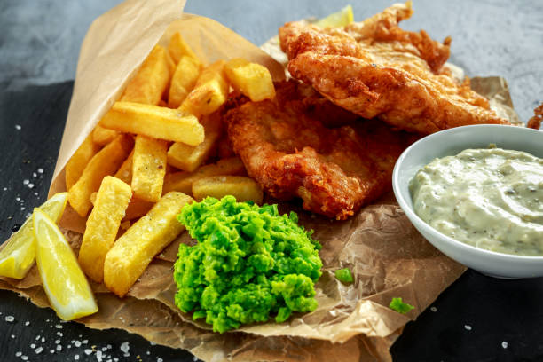 istock British Traditional Fish and chips with mashed peas, tartar sauce on crumpled paper. 675254792