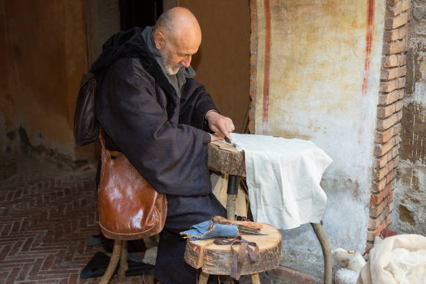 Gorizia, Italy - April 23, 2017: Medieval craftsman cuts leather on historical reenactment in Gorizia castle - Gorizia, Italy.
