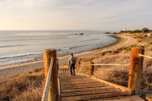istock Man walking at boardwalk to beach, Malibu. 675272086