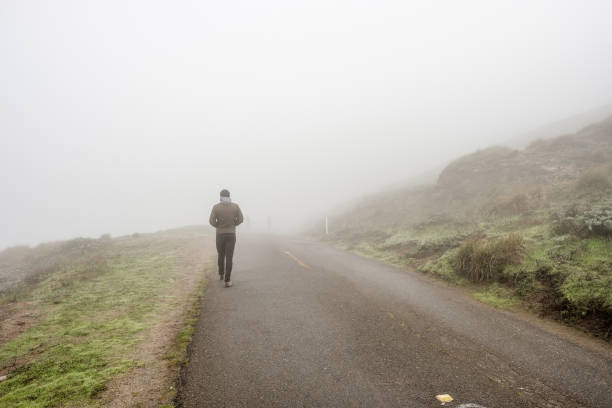 istock Lone man walking through the white fog 675272196