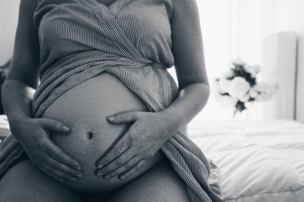 Fermez-vous vers le haut de la femme enceinte touchant son ventre avec des mains - Photo