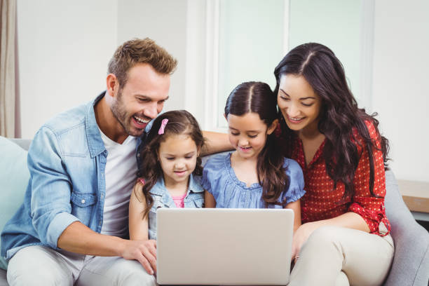 istock Family smiling and looking in laptop on sofa 675278362