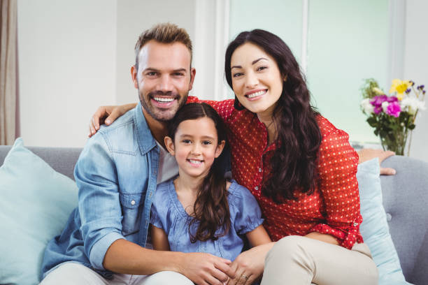 istock Happy parents sitting with daughter on sofa 675278518