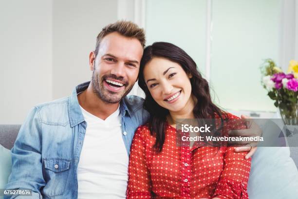 Happy Couple Sitting On Sofa At Home Stock Photo - Download Image Now - 35-39 Years, Couple - Relationship, 30-34 Years