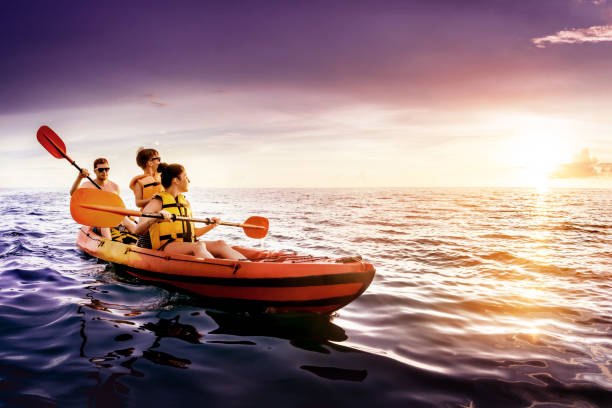szczęśliwa rodzina pływa kajakiem o zachodzie słońca nad morzem - blue kayak zdjęcia i obrazy z banku zdjęć