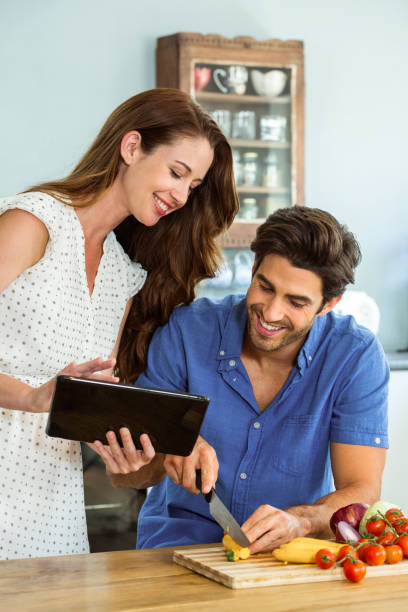 istock Woman using digital tablet and man chopping vegetables 675285032