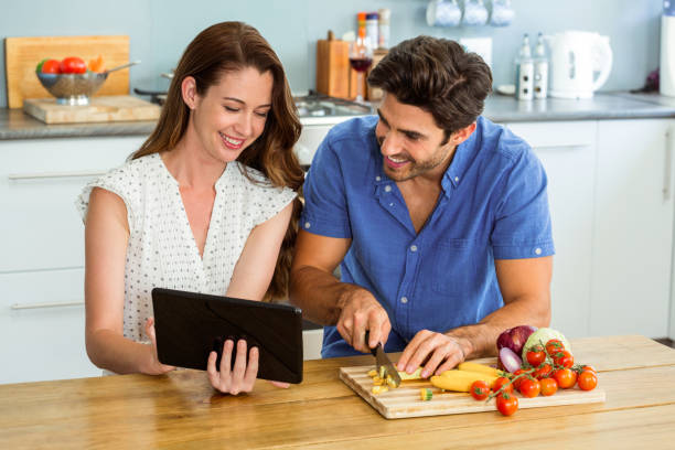istock Woman using digital tablet and man chopping vegetables 675285126