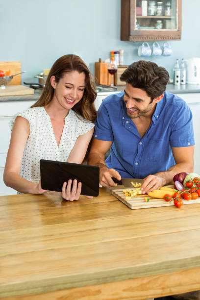 istock Woman using digital tablet and man chopping vegetables 675285260