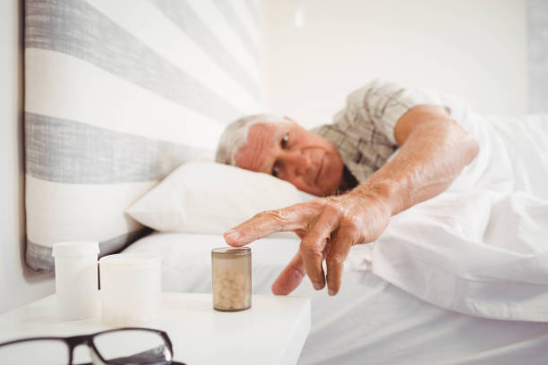 istock Senior man picking up pill bottle 675289432