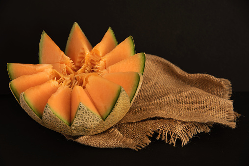 Juicy carving and half cut honeydew melon isolated on black background
