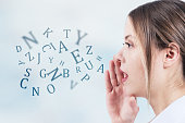 Woman talking with alphabet letters coming out of her mouth. Communication concept