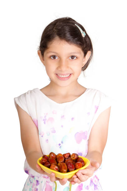 Little Muslim kid presenting a dish of dates for iftar - breaking fast in Holy Ramadan - showing generosity of Ramadan