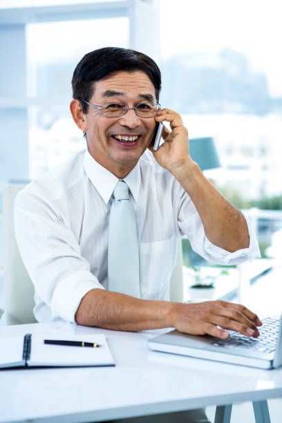 istock Smiling asian businessman calling someone 675301464