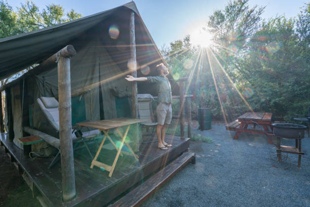 istock Young man standing arms outstretched in front of tent 675301778