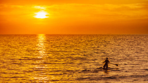 istock Man kneeling on a paddle board at sea before sunset 675303948