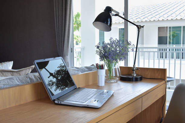 istock wooden table with computer notebook,pencil,lamp and artificial flowers in modern working area 675304576