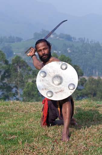 Indian fighter with sword and shield performing Kalaripayattu marital art demonstration in Kerala, South India
