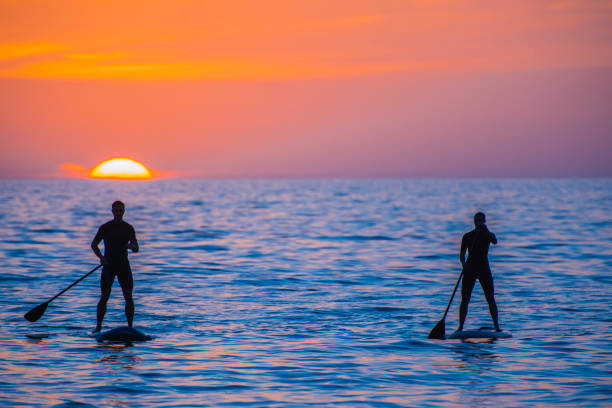 istock Paddle boarder couple at sea during sunset 675304910