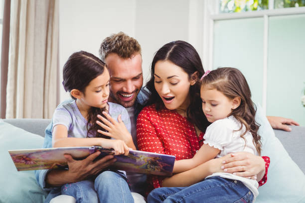 istock Family looking in picture book while sitting on sofa 675310972