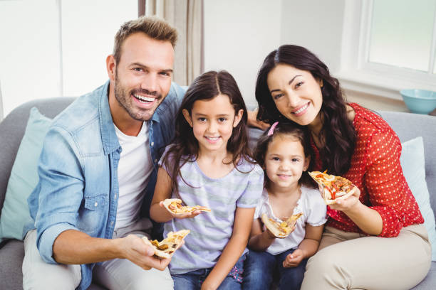 istock Happy family eating pizza while sitting on sofa 675311178