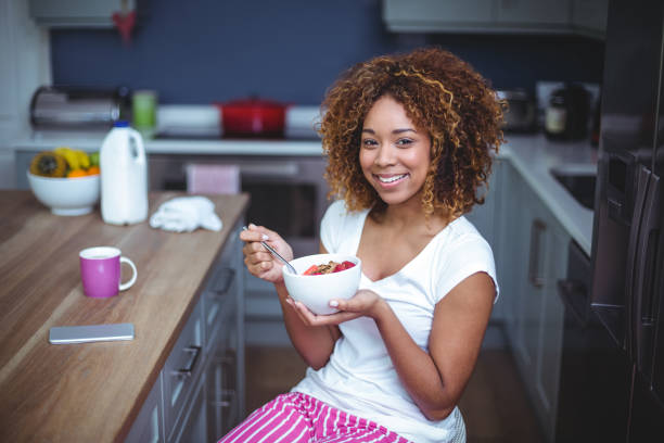istock Happy young woman having breakfast in kitchen 675317838