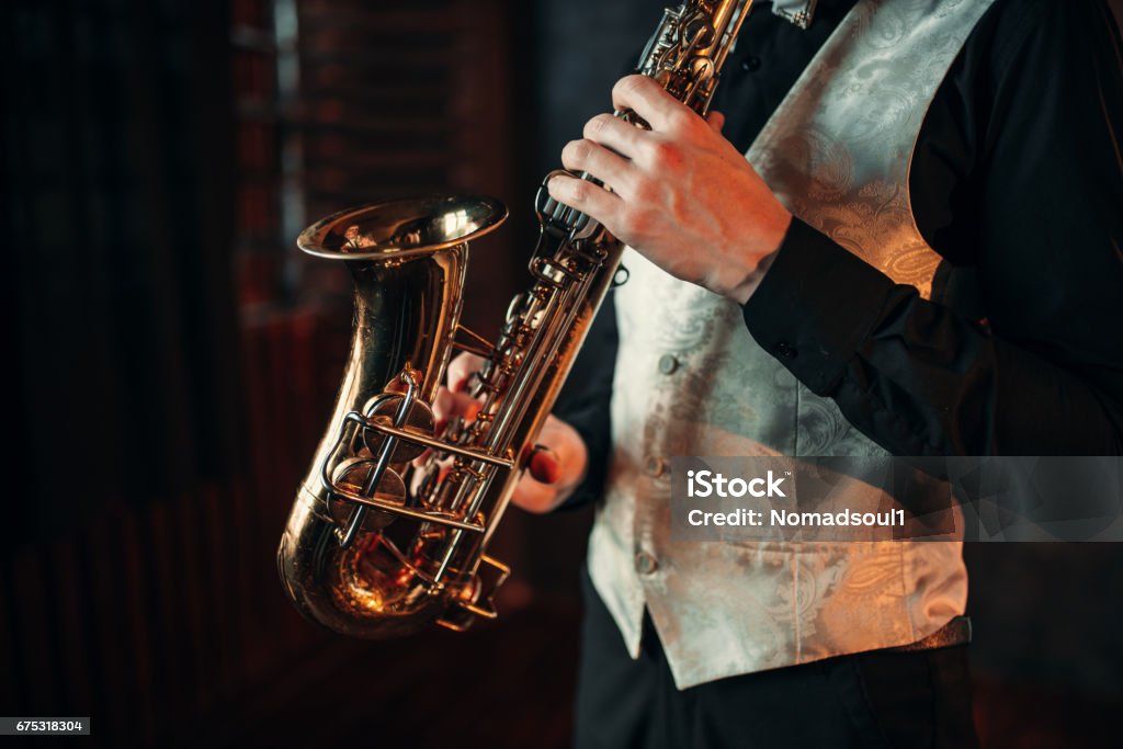 Jazz man hands holding saxophone closeup Jazz man hands holding saxophone closeup. Brass band musical instrument. Solo jazz-man with sax in studio Adult Stock Photo