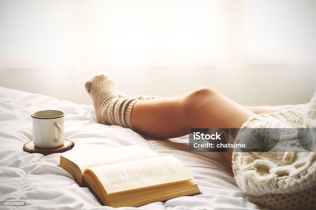 Weiches Foto von Frau auf dem Bett mit altem Buch und Tasse Kaffee - Lizenzfrei Frauen Stock-Foto