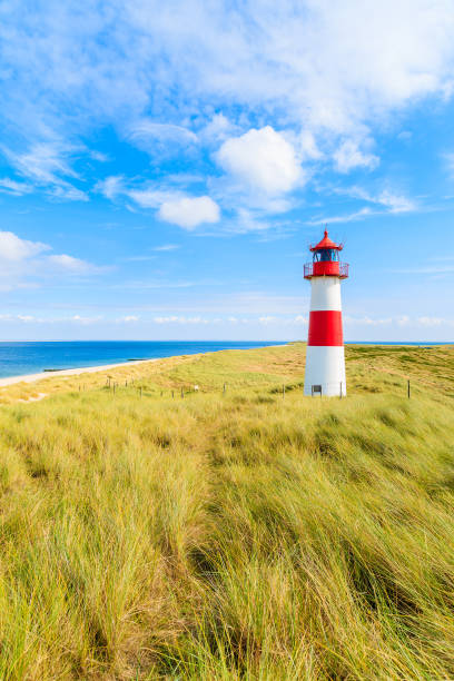 ellenbogen faro duna de arena contra el cielo azul con nubes blancas en la isla de la costa norte de sylt, alemania - lighthouse beacon north sea coastal feature fotografías e imágenes de stock