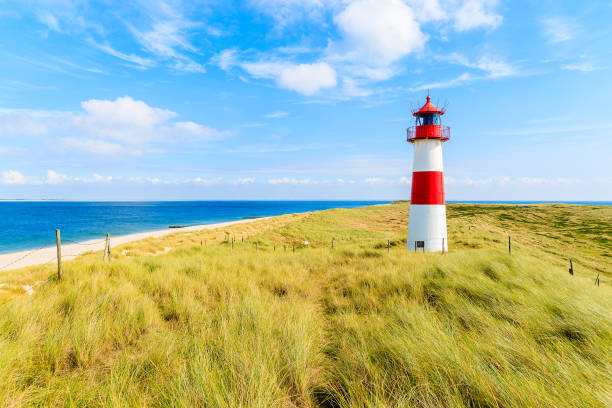 istock Ellenbogen lighthouse on sand dune against blue sky with white clouds on northern coast of Sylt island, Germany 675331498