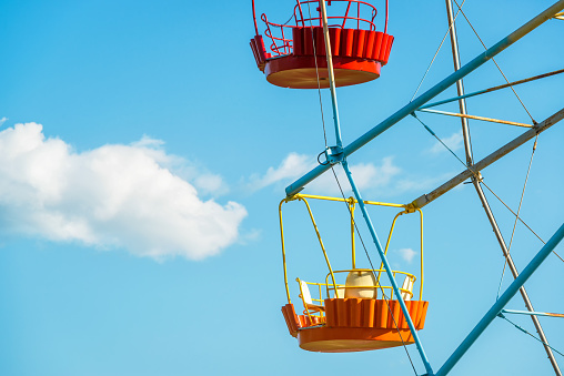 Colorful cabins of Ferris wheel on a background of blue sky with cloud