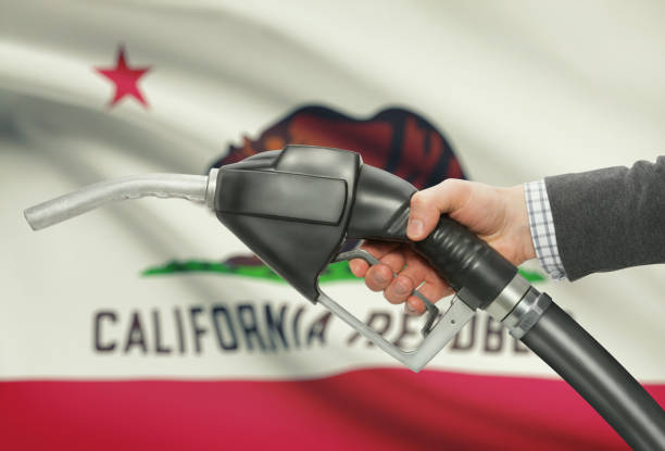 Fuel pump nozzle in hand with USA states flags on background - California stock photo