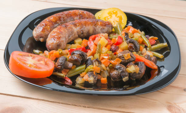 istock Fried sausages with vegetables on a kitchen table with tomatoes 675341184